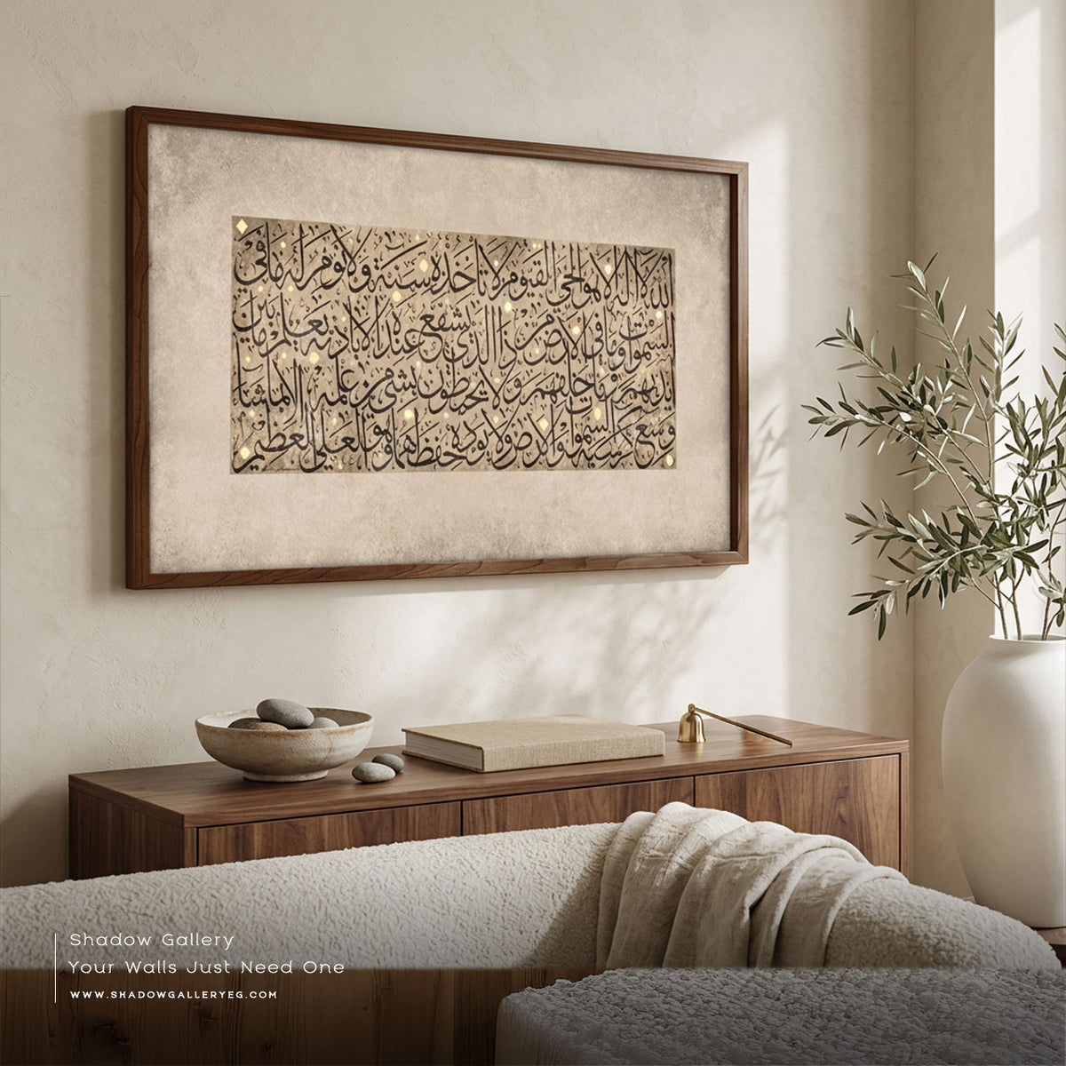 Ayatul Kursi calligraphy canvas in a dark wood frame above a walnut sideboard with an olive branch in a white vase